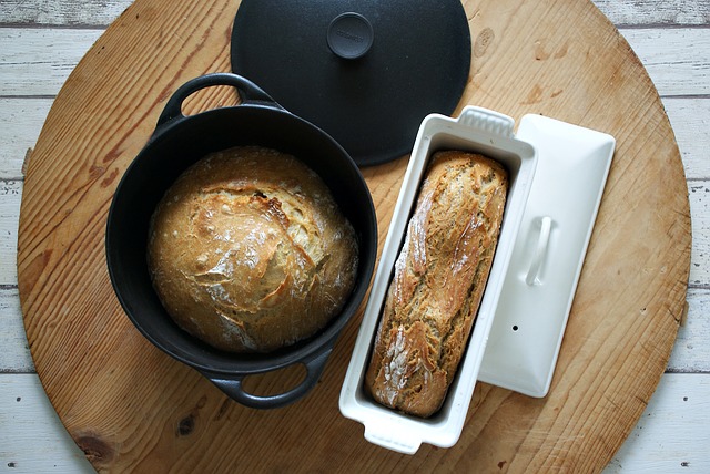 Auf einem runden Holztisch stehen zwei gebackene Brote, eins in einer Kuchenform, eins in einem Topf.