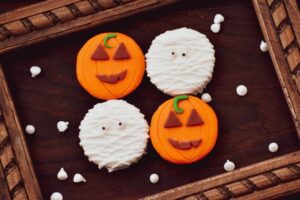 Vier Halloween-Kekse, zwei Mumien, zwei Kürbisse, liegen auf einem Tablett nebeneinander