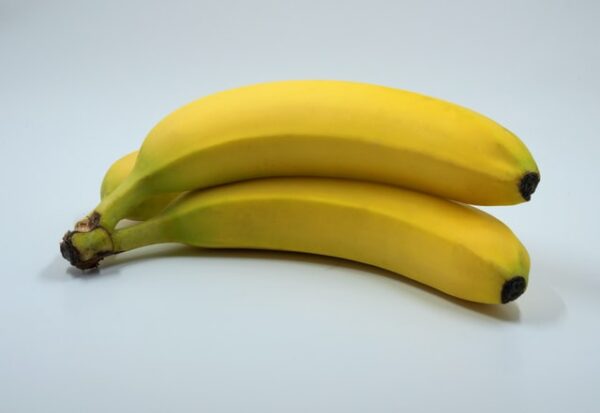 Drei gelbe Bananen liegen vor einem weißen Hintergrund.