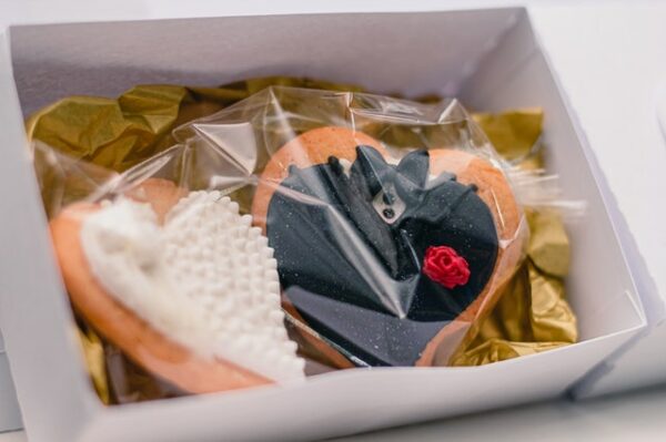 Zwei herzförmige Kekse, die wie Braut und Bräutigam verziert sind, liegen in einer Box