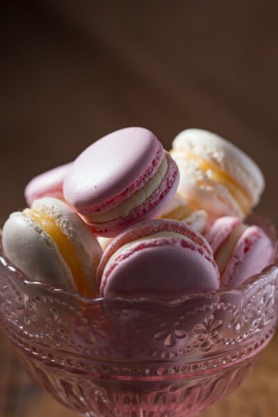 In einer kleinen Glasschale stapeln sich weiße und rosane Macarons