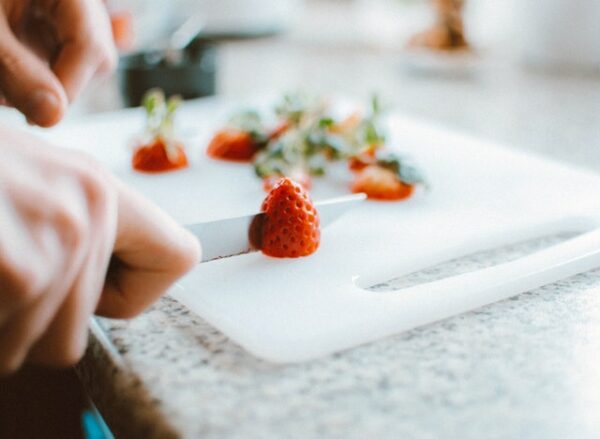 Erdbeeren werden auf einem weißen Brett in Scheiben geschnitten