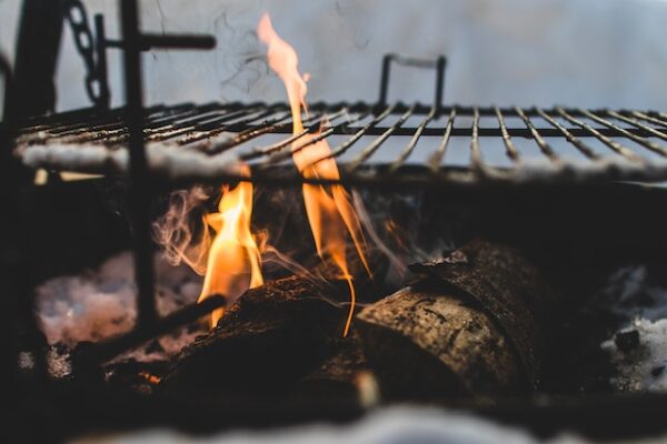 Ein Grillrost über einer offenen Flamme und Holzscheiten