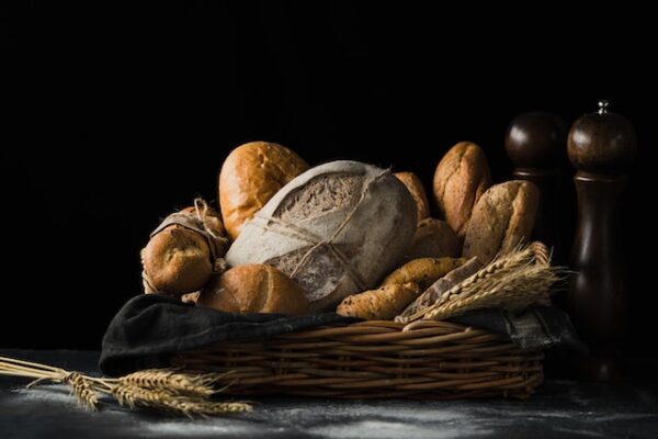 In einem Korb liegen neben einigen Getreideähren verschiedene Brotsorten