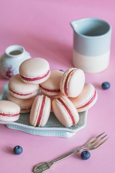 Auf einem kleinen Teller liegen mit einer pinken Creme gefüllte rosa Macarons